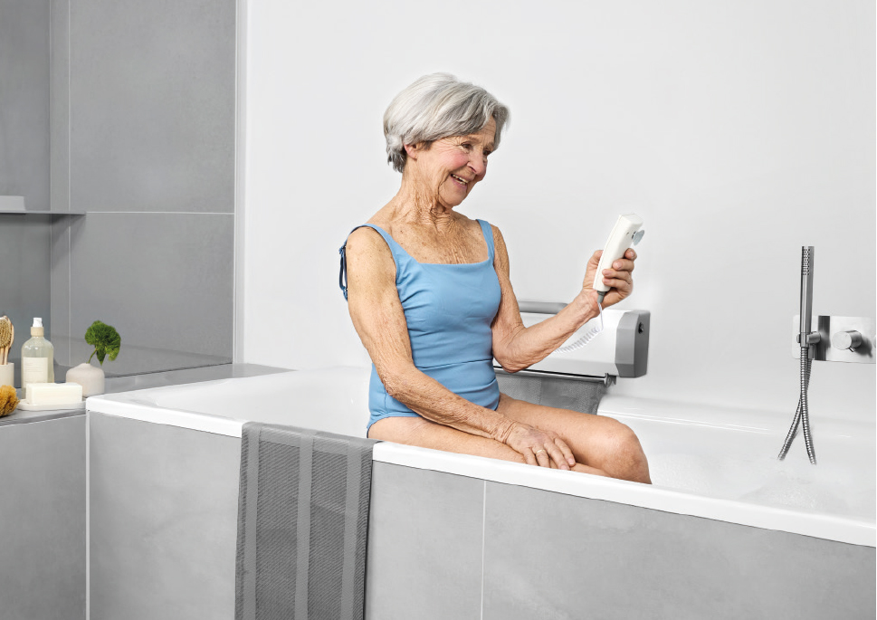 Seniorin bedient per Handsteuerung den Badelift in der Badewanne